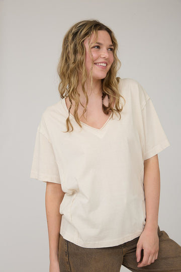 woman wearing a beige v-neck oversized t-shirt with short sleeves and a relaxed fit