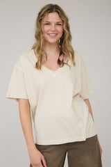 woman wearing a cream oversized v-neck t-shirt with short sleeves and relaxed fit