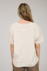 woman wearing a beige oversized t-shirt with a unique stitch detail on the back