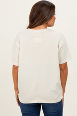woman wearing a light beige oversized maternity t-shirt with a back seam detail and short sleeves