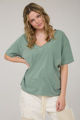 woman wearing a green oversized v-neck top with relaxed sleeves and subtle stitching details
