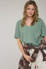 woman wearing a green v-neck oversized t-shirt with a plaid shirt tied around her waist