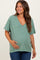 woman wearing a green v-neck maternity top and holding her baby bump