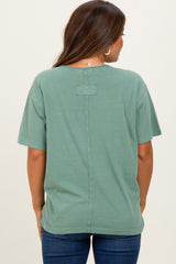 woman wearing a green short sleeve maternity top with a stitched back detail