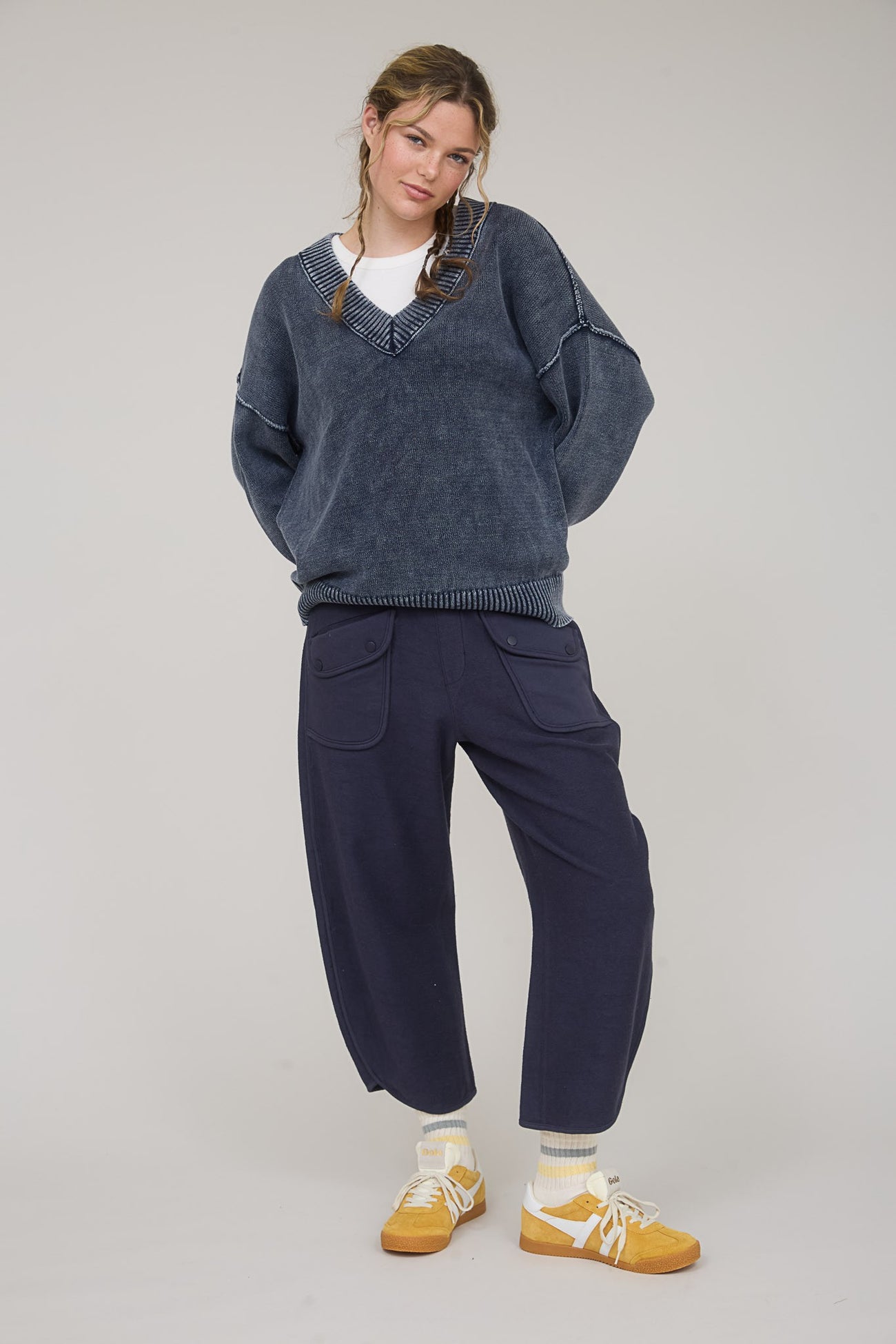 woman wearing a dark blue oversized sweater and navy wide-leg pants paired with yellow sneakers