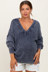 woman wearing a gray maternity sweater with a deep v-neck and wide sleeves, showcasing her baby bump