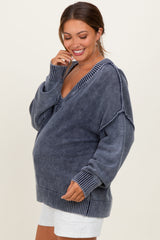woman wearing a dark gray oversized maternity sweater with a deep v-neck and ribbed details, showcasing her baby bump
