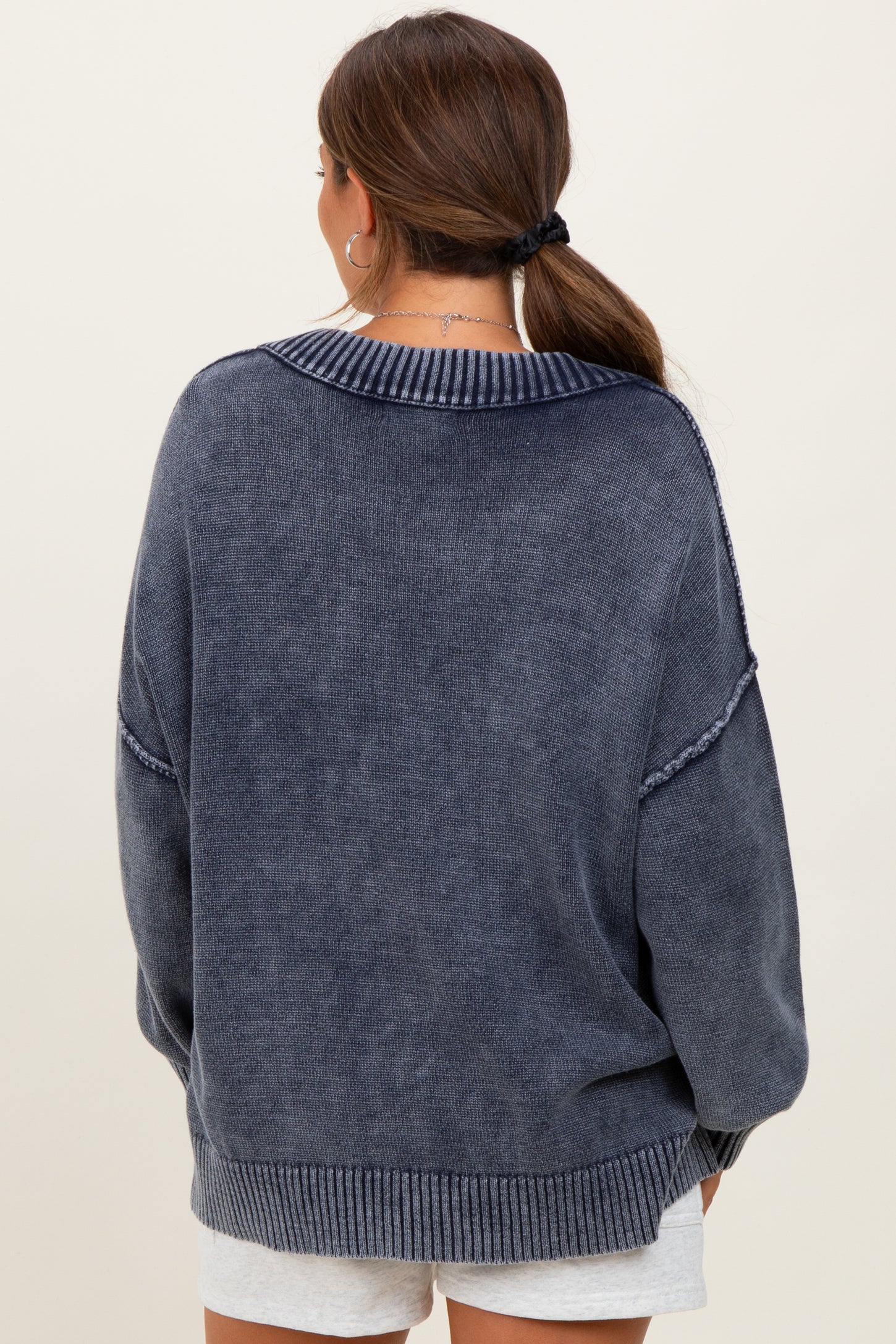 woman wearing a navy blue oversized maternity sweater, viewed from the back, with a ribbed collar and cuffs