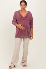 woman wearing a mauve oversized maternity sweater with v-neck and ribbed details, holding her baby bump