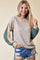 woman wearing a beige and green color block hoodie with striped sleeves and distressed denim shorts