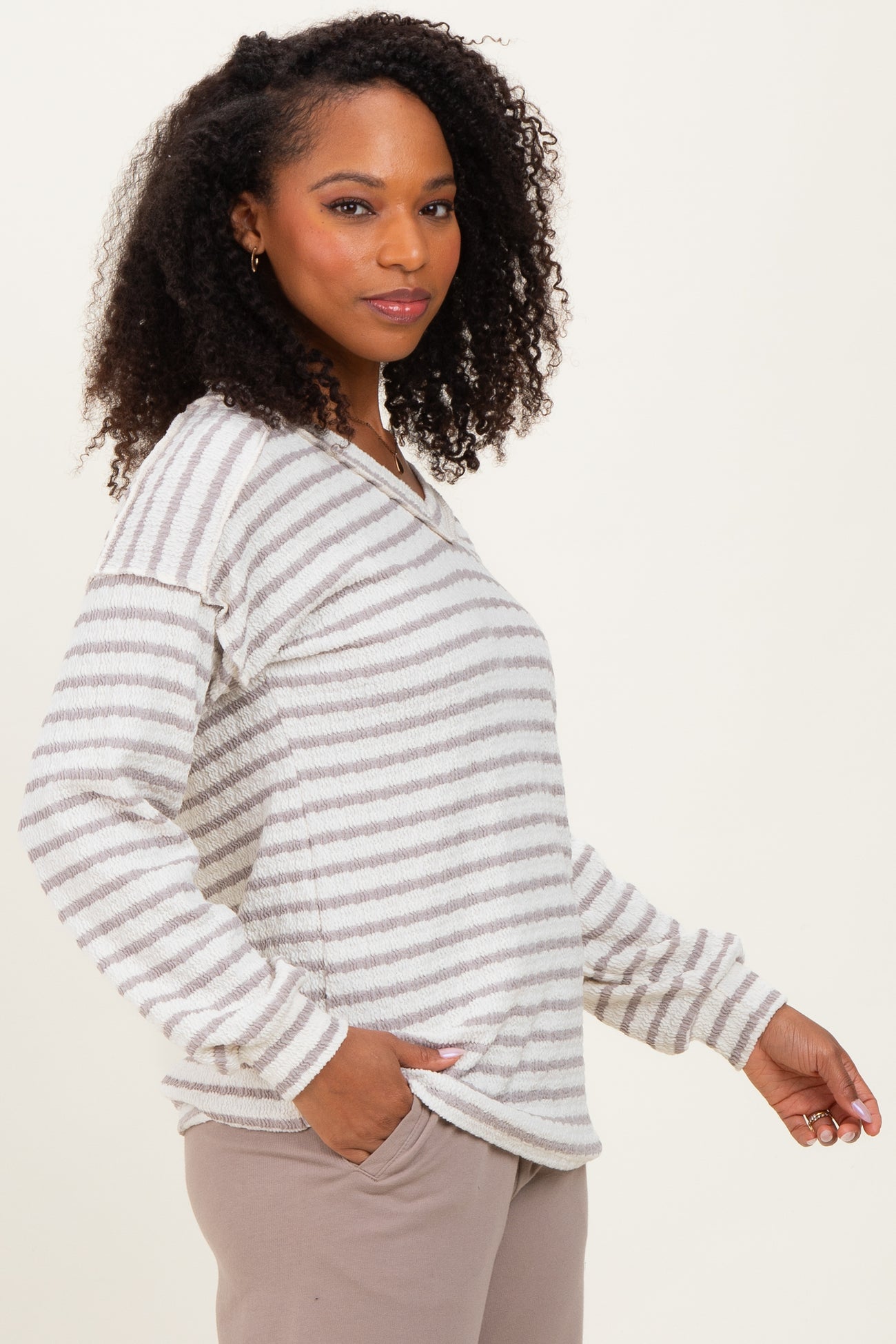 woman wearing a gray and white striped long sleeve top with a relaxed fit and side pockets