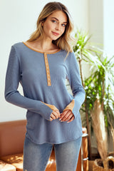 woman wearing a blue long sleeve henley top with button detailing and contrasting neckline, styled with light wash jeans