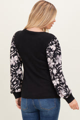 woman wearing a black sweater with floral puff sleeves and blue jeans, shown from the back
