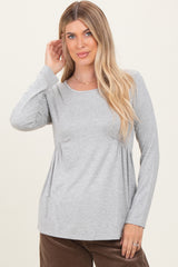 woman wearing a gray long sleeve top with gathered detailing at the waist