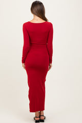 woman wearing a long red fitted maternity dress with long sleeves, viewed from the back