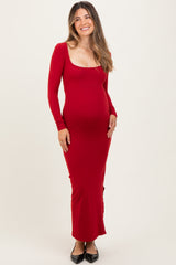 woman wearing a red long sleeve maternity dress with a scoop neckline and visible baby bump