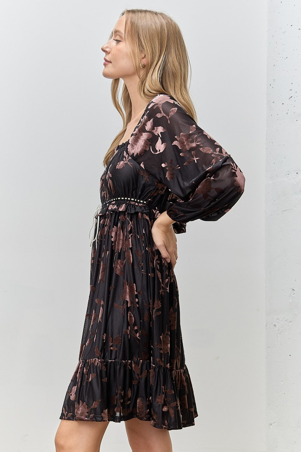 woman wearing a black floral print puff sleeve dress with a tiered skirt and a drawstring waist