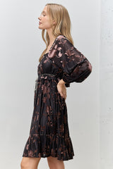 woman wearing a black floral print puff sleeve dress with a tiered skirt and a drawstring waist
