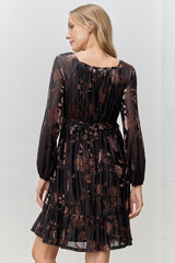 woman wearing a black floral print dress with long sleeves and a tiered hem, view shows the back of the dress