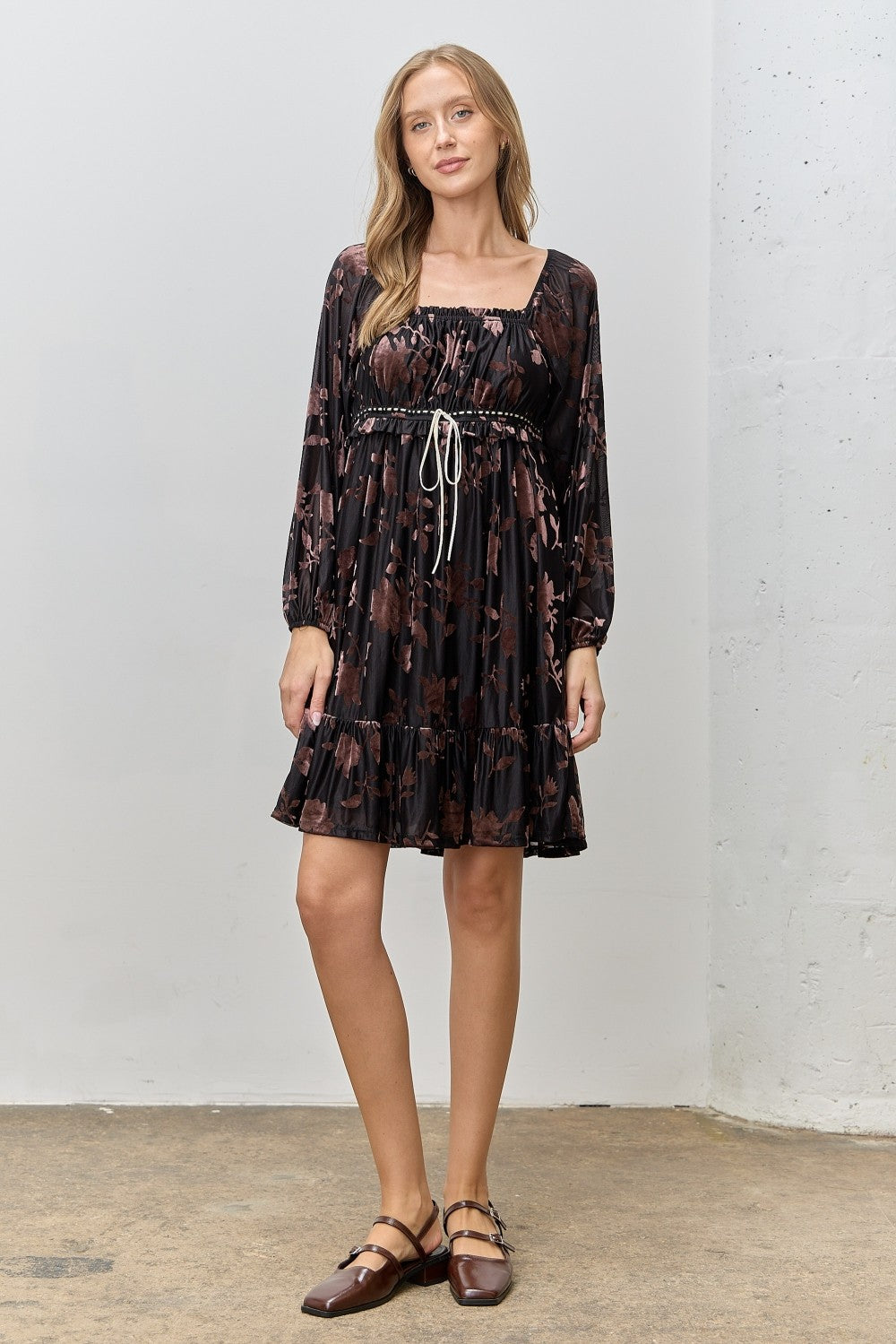 woman wearing a black floral print short dress with puff sleeves and a tied waist detail