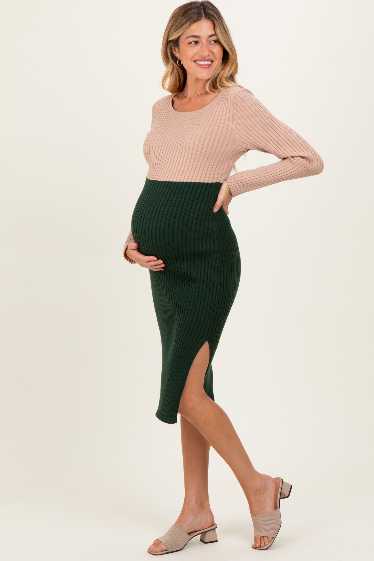 woman wearing a ribbed maternity dress with a beige top and green skirt, showing her baby bump and a side slit