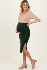 woman wearing a ribbed maternity dress with a beige top and green skirt, showing her baby bump and a side slit