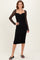 woman wearing a black ruched midi dress with long lace sleeves and a sweetheart neckline, standing in a relaxed pose
