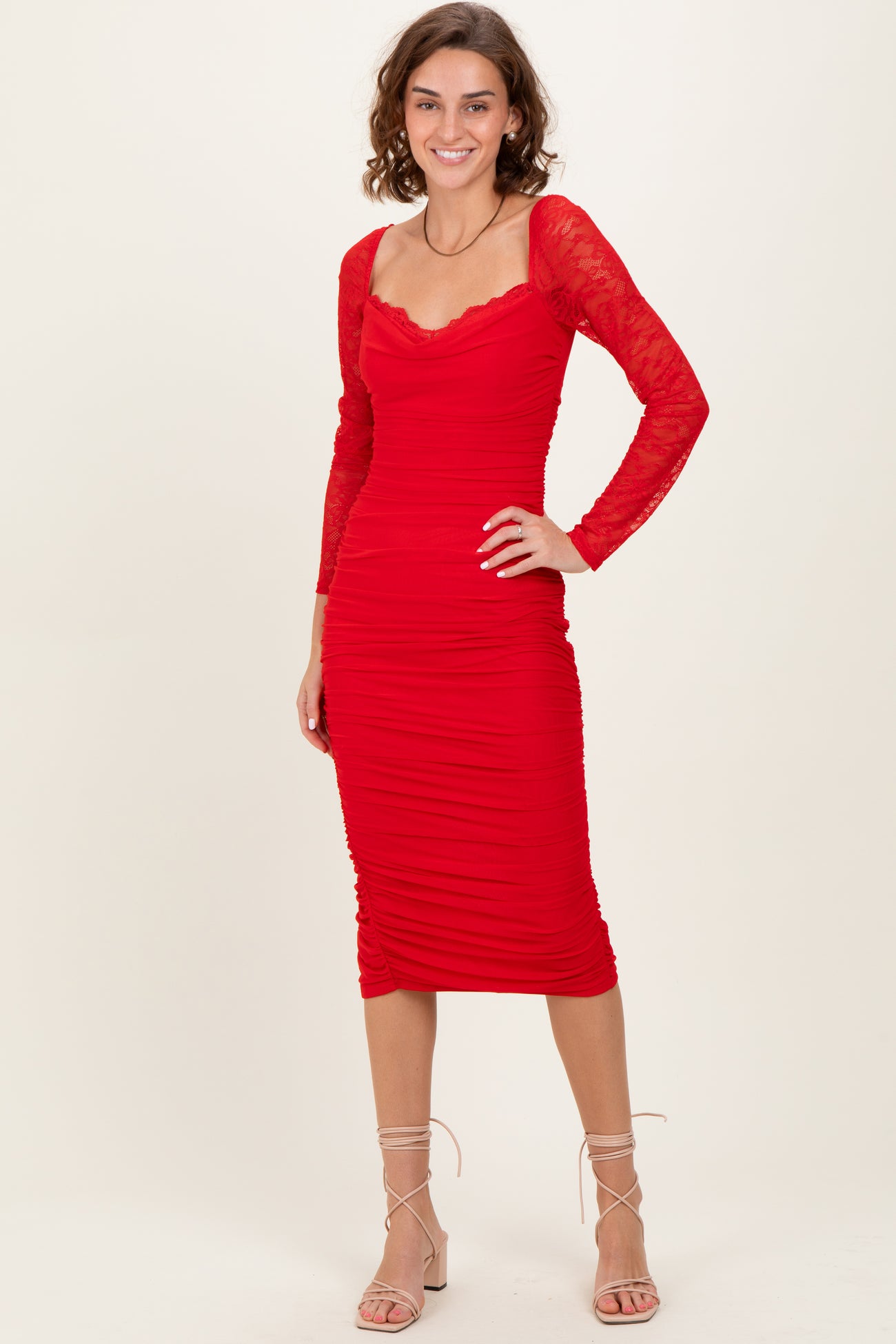 woman wearing a red midi dress with lace long sleeves and ruched detail