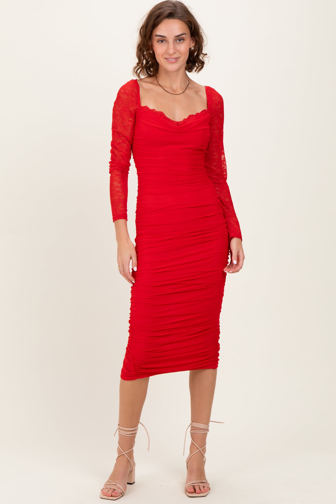 woman wearing a red long sleeve bodycon dress with ruched detailing and lace sleeves