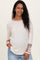 woman wearing a cream ribbed maternity top with colorful patterned sleeve details and a visible baby bump