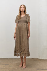 woman wearing a brown floral embroidered maxi dress with short sleeves and a smocked bodice.
