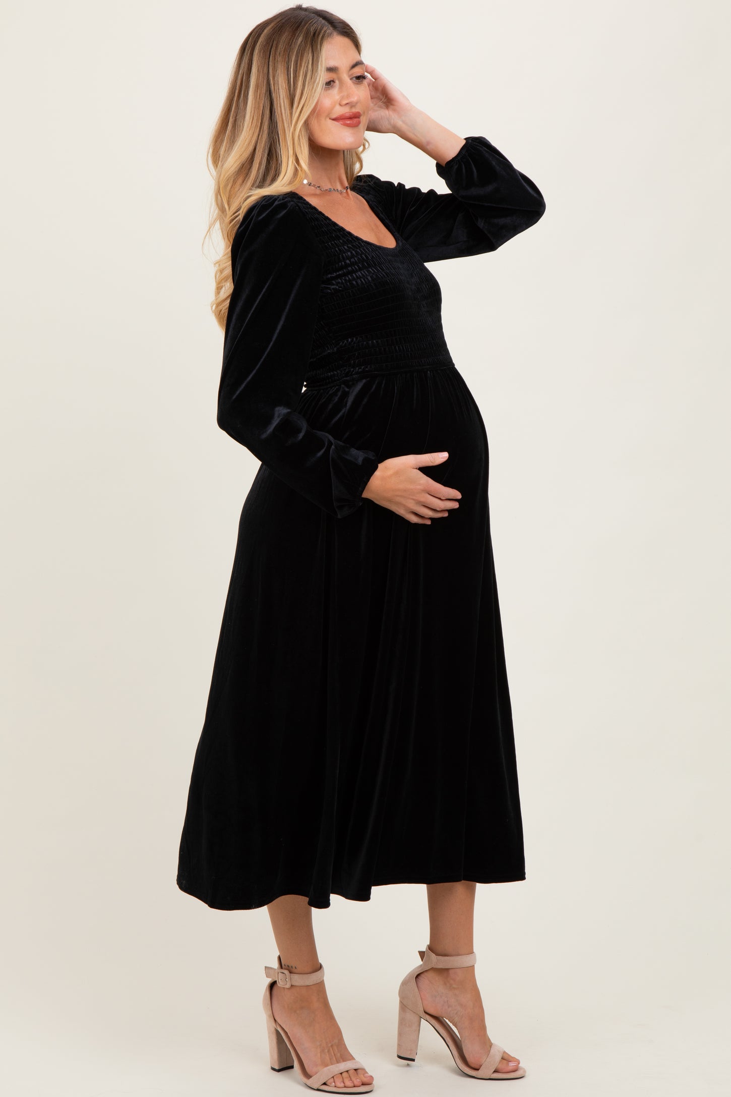 woman wearing a black velvet maternity dress with long sleeves and a flowy silhouette, showing her baby bump