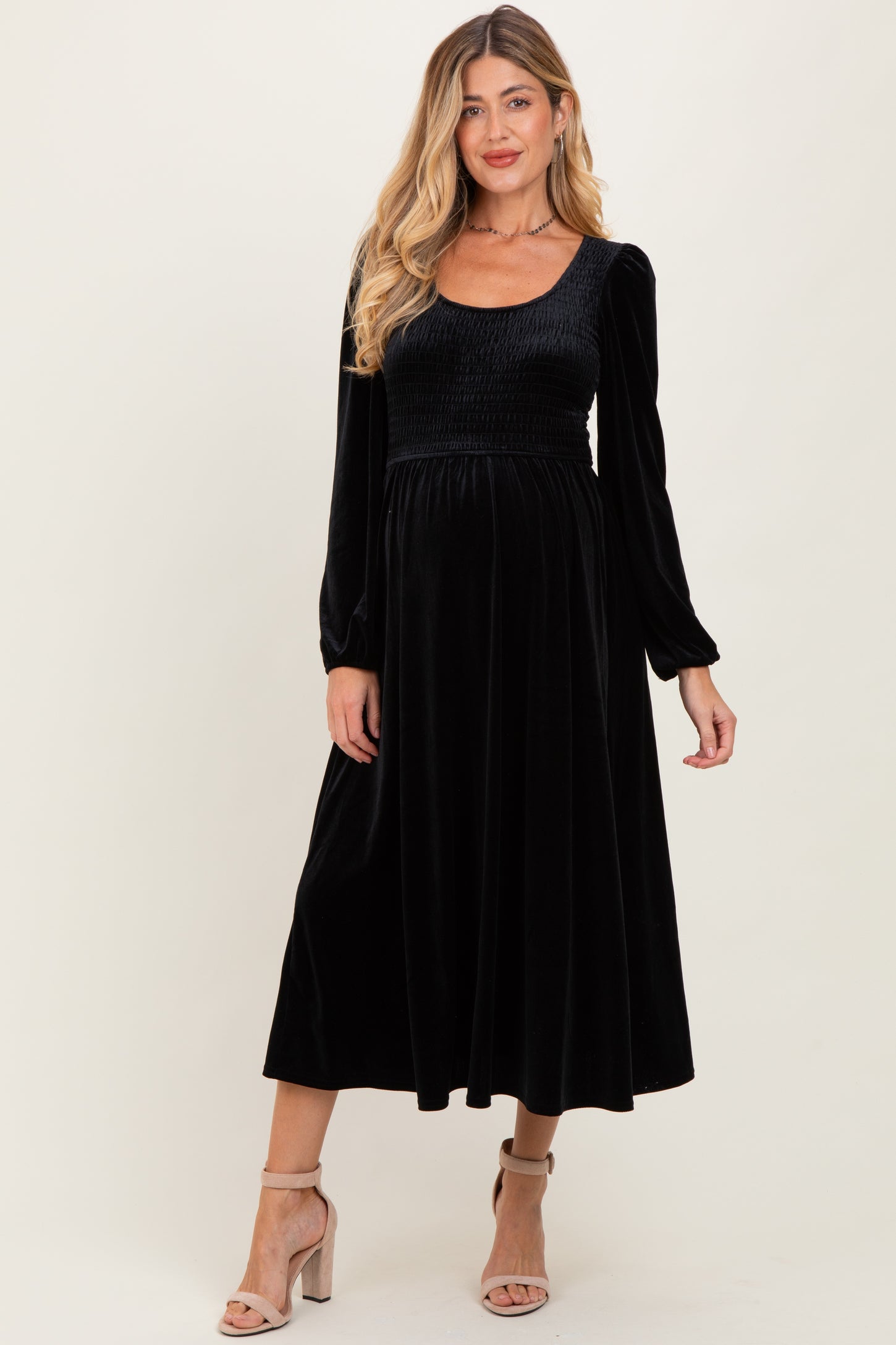 woman wearing a black velvet maternity dress with long sleeves and a fitted bodice, showing a baby bump