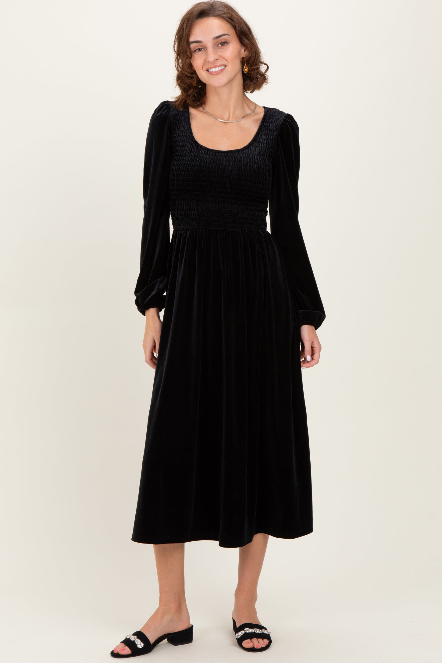 woman wearing a black velvet midi dress with long puff sleeves and a smocked bodice