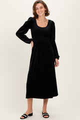 woman wearing a black velvet long sleeve midi dress with a square neckline and smocked bodice, smiling
