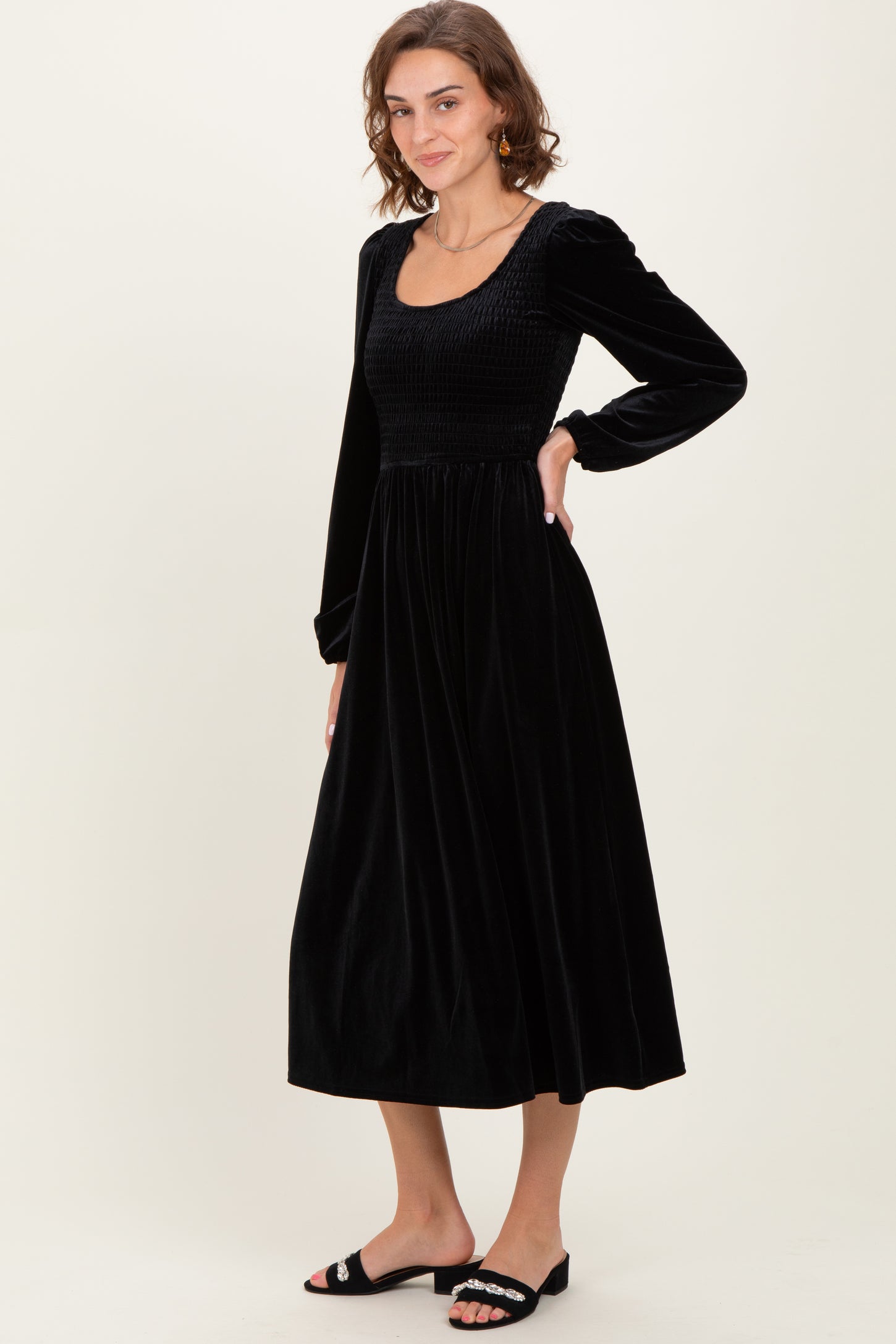 woman wearing a black velvet long sleeve midi dress with a smocked bodice and relaxed fit