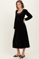 woman wearing a black velvet long sleeve midi dress with a smocked bodice and relaxed fit