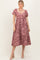 woman wearing a mauve floral print midi dress with puff sleeves and a square neckline, posing with a neutral background
