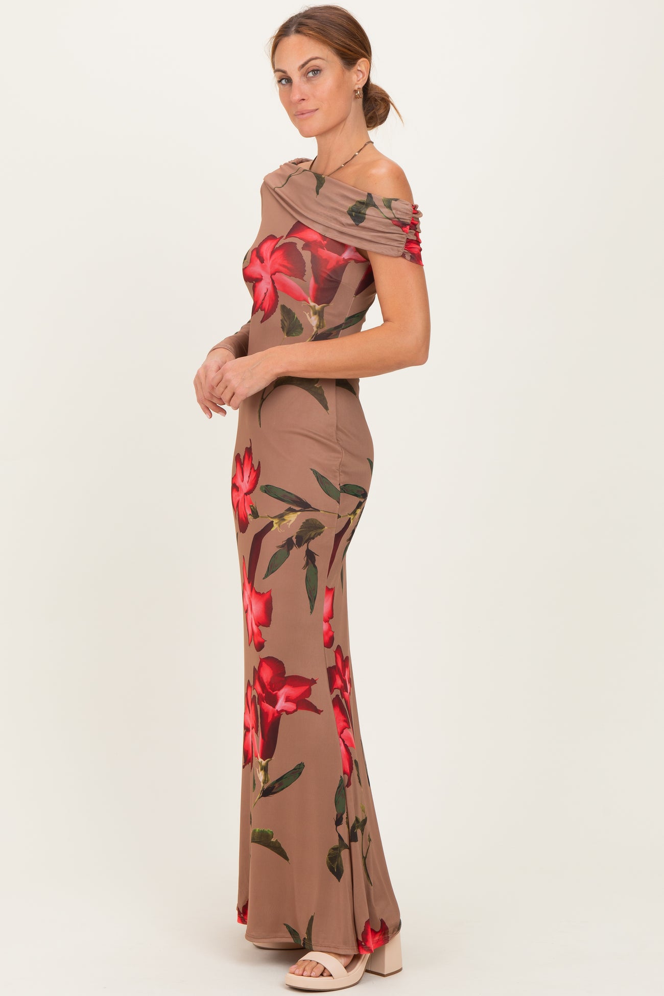 woman wearing a beige off-shoulder gown with red floral prints and a fitted silhouette