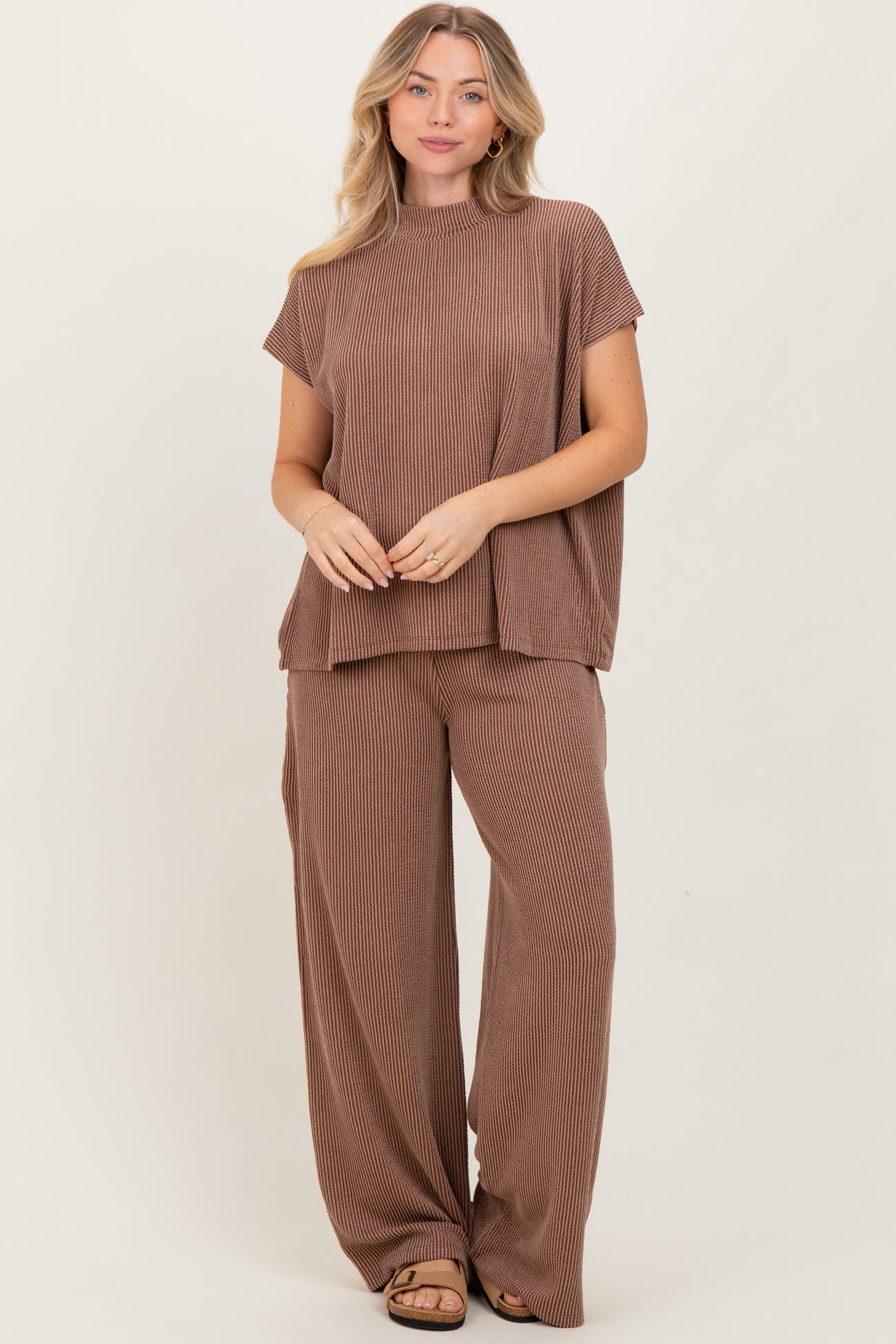woman wearing a brown striped short sleeve top and wide-leg pants set, standing against a neutral background