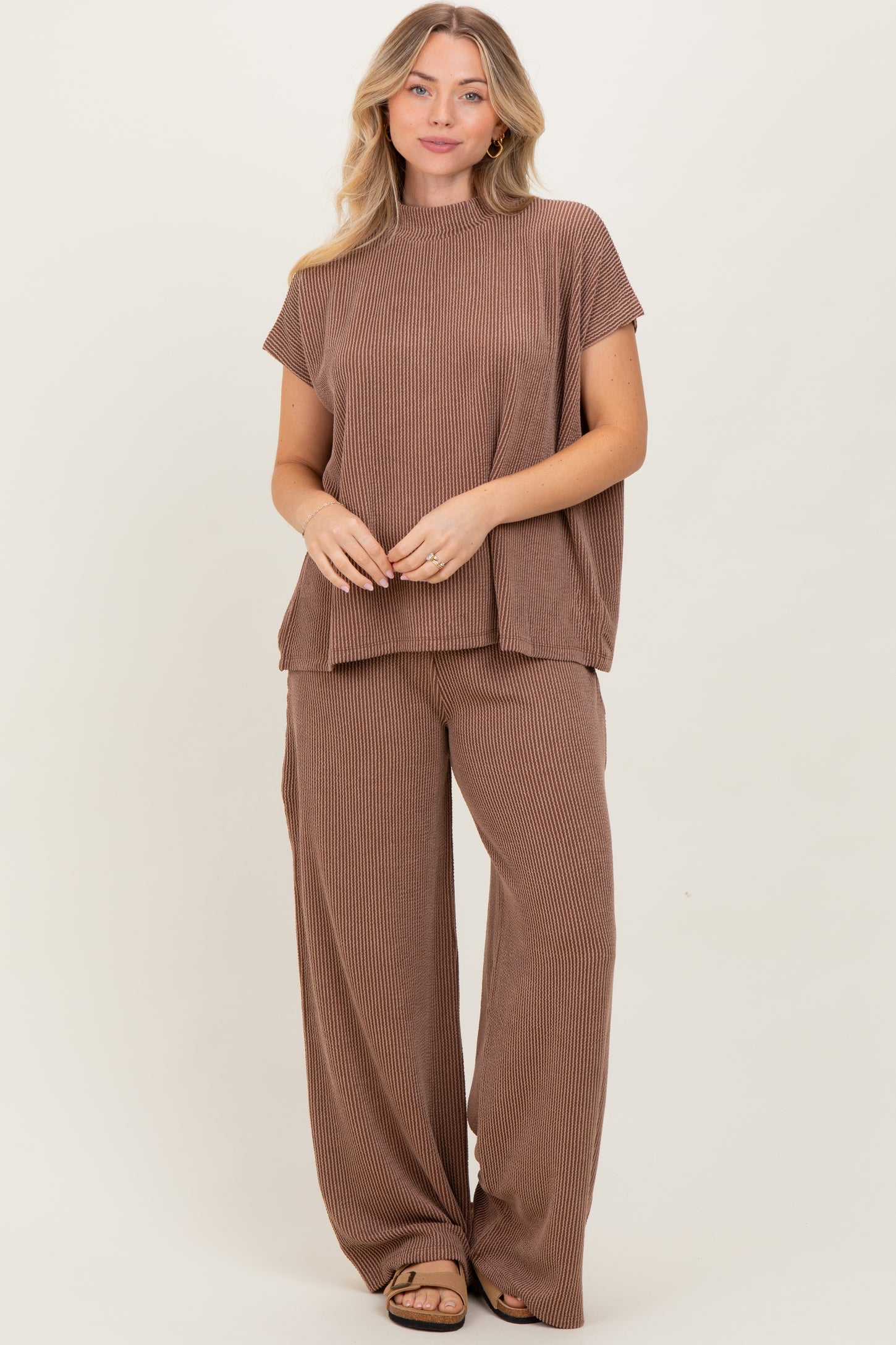 woman wearing a brown striped short sleeve top and wide-leg pants set, standing against a neutral background