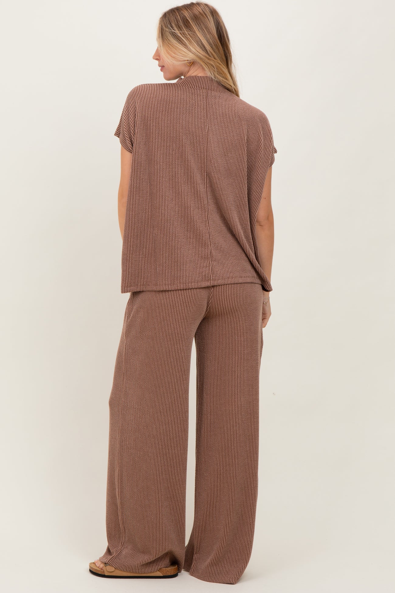 woman wearing a brown striped short sleeve top and wide-leg pants, viewed from the back