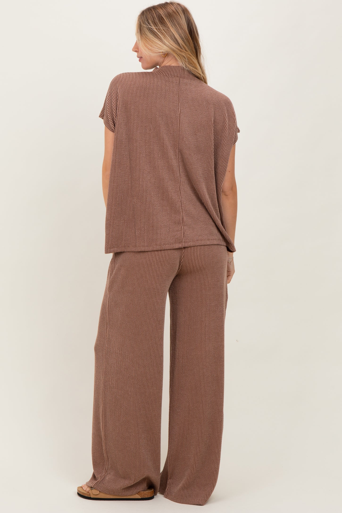 woman wearing a brown striped short sleeve top and wide-leg pants, viewed from the back