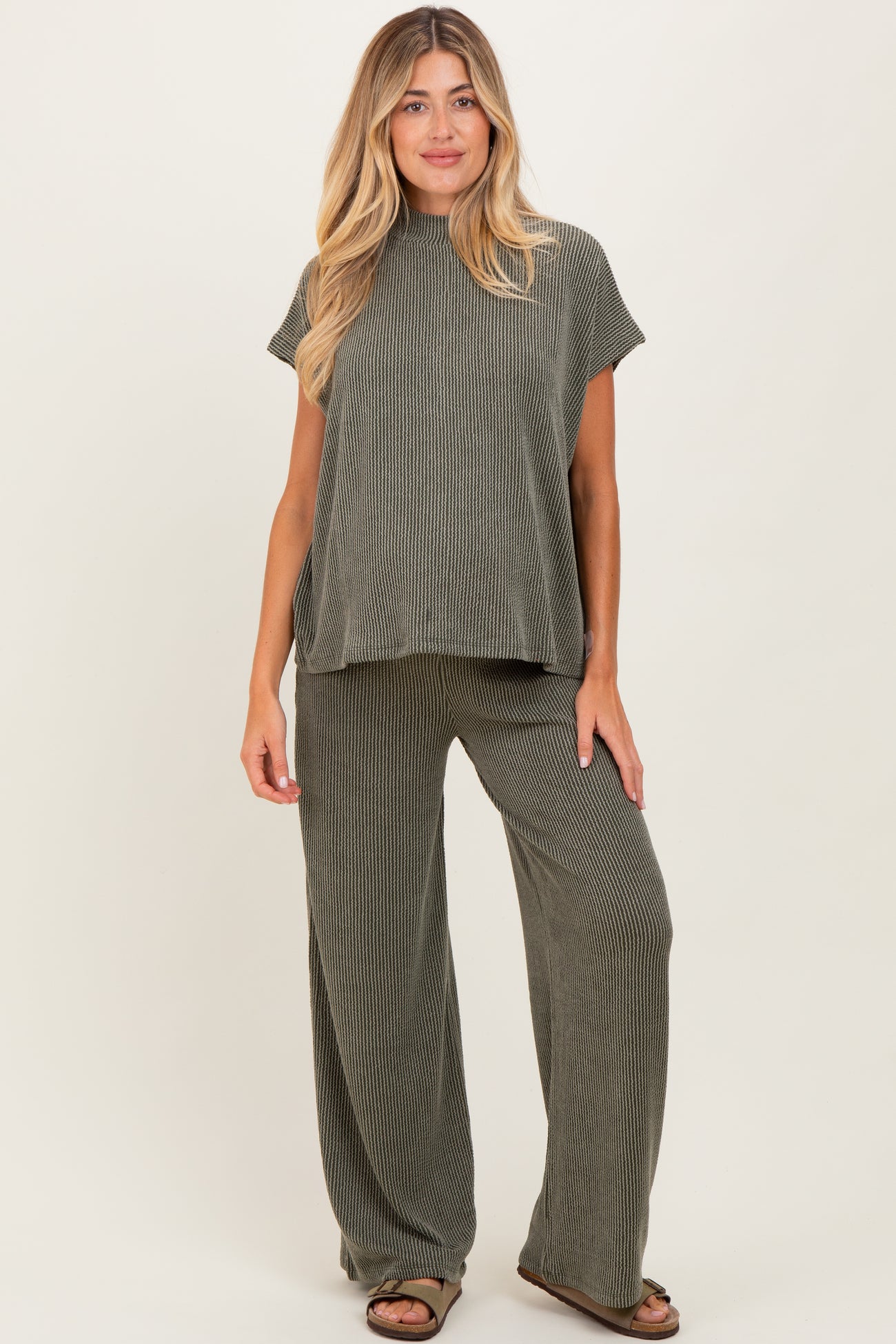 woman wearing a green ribbed maternity lounge set with a short sleeve top and wide-leg pants