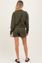 woman wearing an olive green maternity sweatshirt and matching shorts, showing her back and casual style