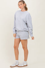 woman wearing a gray oversized sweatshirt and matching shorts with a relaxed fit and white sneakers