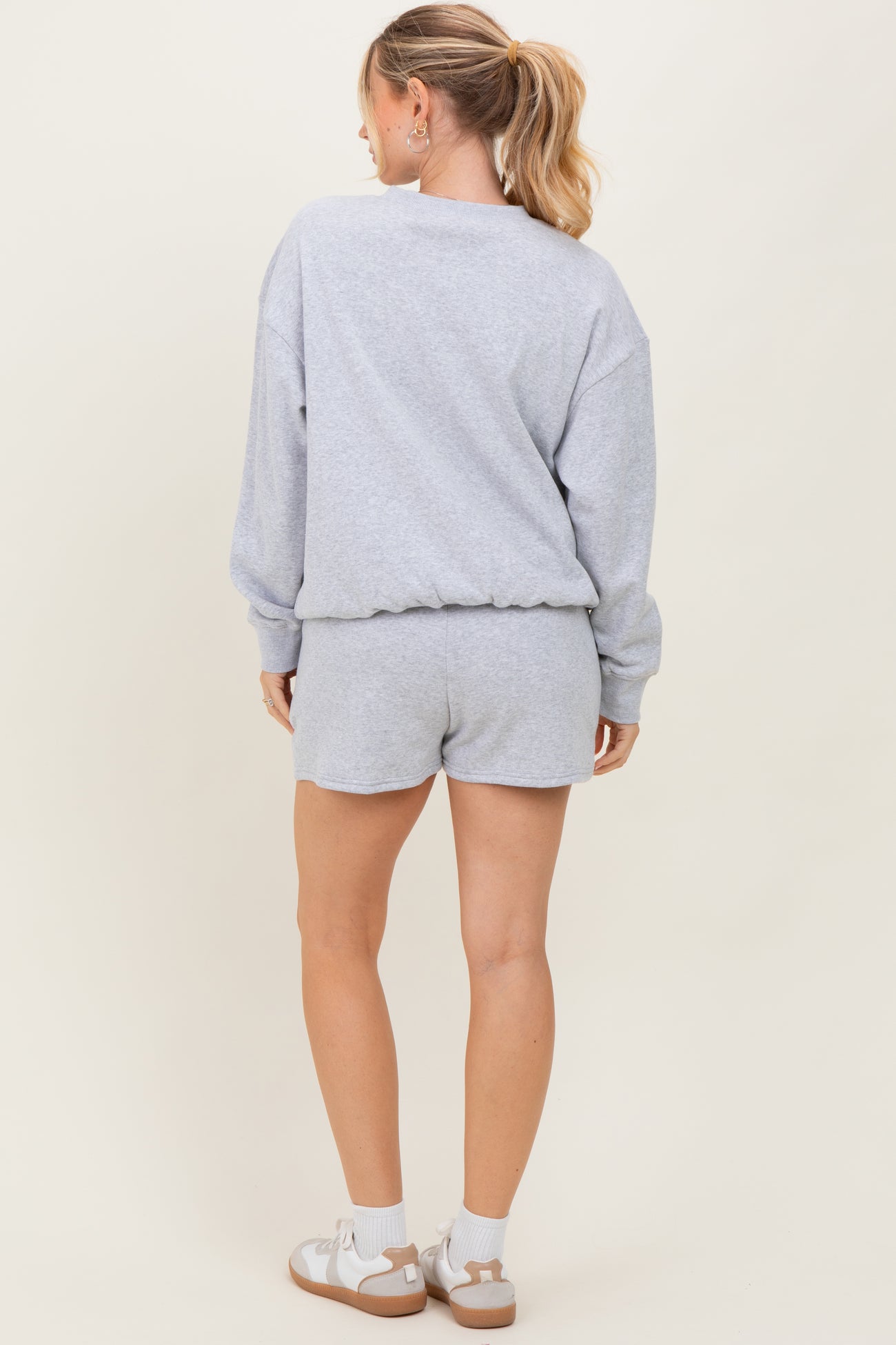 woman wearing a gray relaxed fit sweatshirt and matching shorts, seen from the back