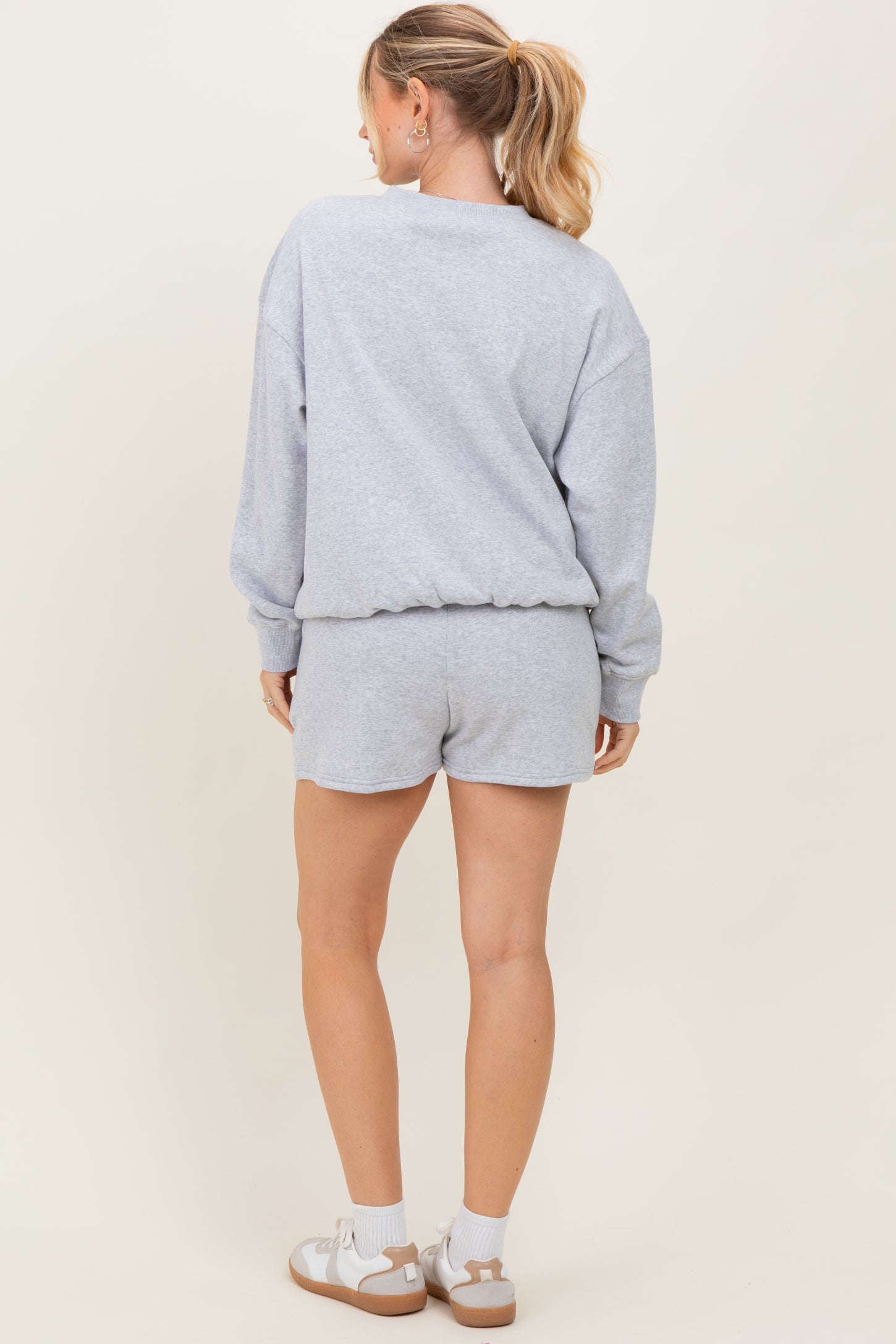 woman wearing a gray relaxed fit sweatshirt and matching shorts, seen from the back