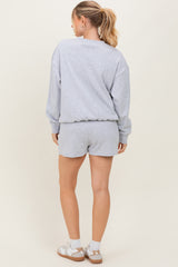 woman wearing a gray relaxed fit sweatshirt and matching shorts, seen from the back