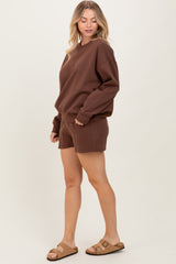 woman wearing a brown oversized sweatshirt and matching shorts with sandals